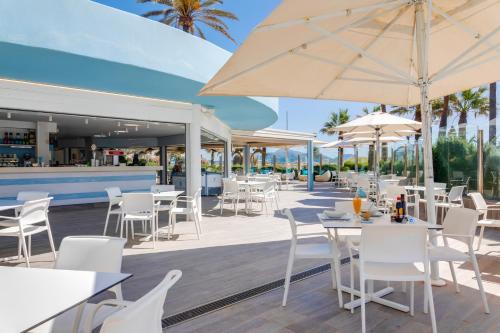 a restaurant with white chairs and tables and umbrellas at Playa Esperanza Resort Affiliated by Meliá in Playa de Muro
