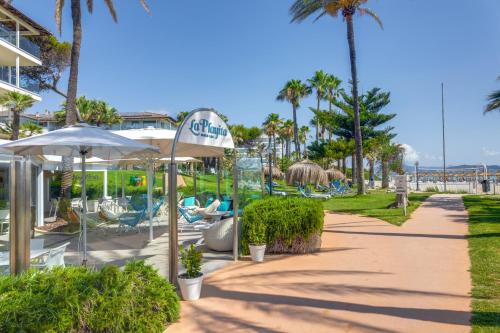 a resort pathway with chairs and umbrellas and palm trees at Playa Esperanza Resort Affiliated by Meliá in Playa de Muro