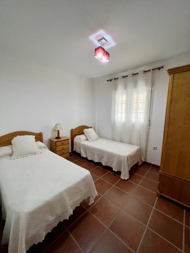 two beds in a room with white walls and tile floors at Vivienda Vacacional VELEFIQUE in Velefique