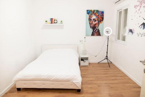 a white bedroom with a bed and a floor lamp at Bride House haifa in Haifa