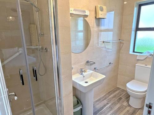 ein Bad mit einer Dusche, einem Waschbecken und einem WC in der Unterkunft Quilty Holiday Cottages - Type B in Quilty