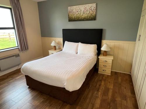 a bedroom with a large bed and two night stands at Quilty Holiday Cottages - Type B in Quilty
