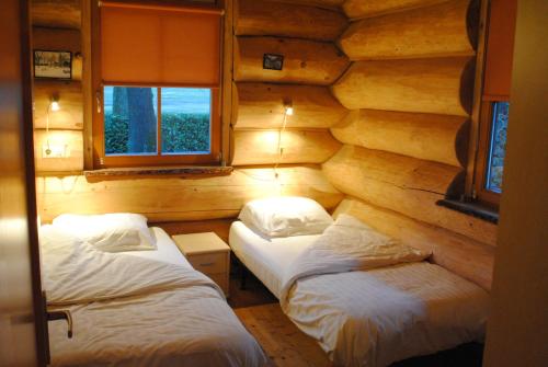 2 camas en una habitación con paredes de madera en Boomgalows De Roestelberg, en Kaatsheuvel