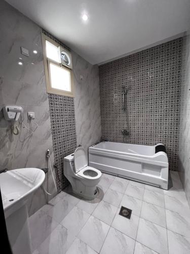 ein Badezimmer mit einer Badewanne, einem WC und einem Waschbecken in der Unterkunft شاليهات وايت هافن - ابها in Chamis Muschait