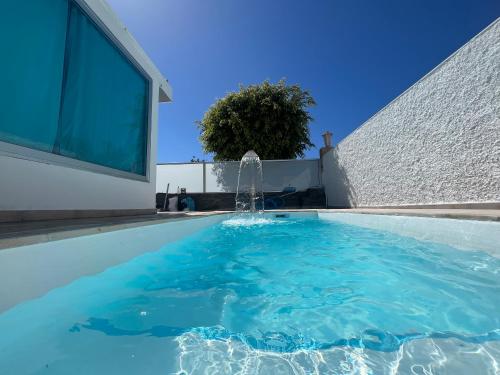 a swimming pool with a fountain in front of a building at The Yumbo Pearl in Playa del Ingles