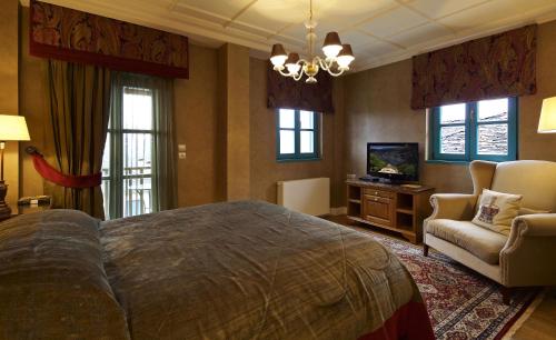 a bedroom with a large bed and a chair and a television at Zagori Suites Luxury Residences in Vitsa