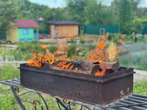 a barbecue grill with fire in a yard at Панівецька Садиба in Zubrivka