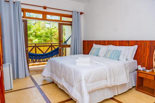 a bedroom with a white bed and a sliding glass door at Pousada Coco Cabana in Camocim