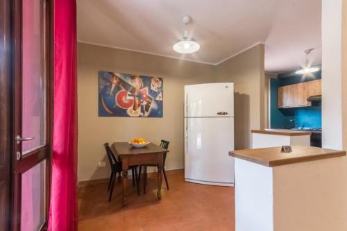 a kitchen with a table and a white refrigerator at Villa con grande giardino ad 800 mt dal mare in Capitana