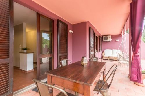 comedor con paredes rosas y mesa y sillas de madera en Villa San Lorenzo, en Capitana