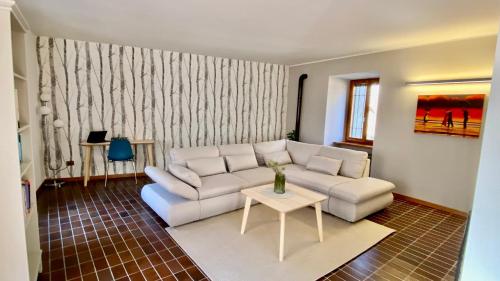 a living room with a white couch and a table at La casa della Rocca - MonferratoHome in Camagna Monferrato