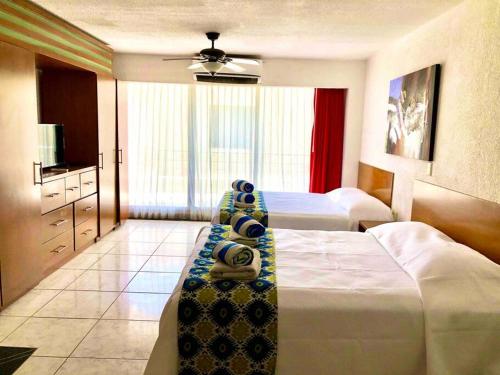a hotel room with two beds and a television at 3 Room Beach Condo, Great for Family and Friends! in Cancún