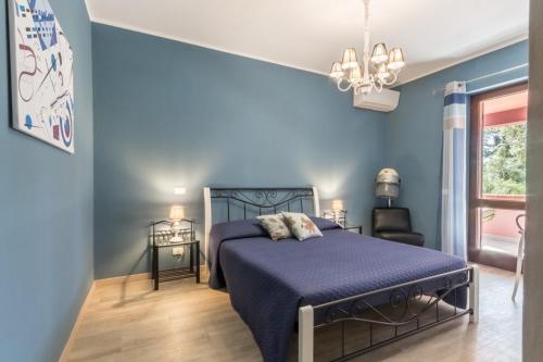 a blue bedroom with a bed and a window at Villa con grande giardino ad 800 mt dal mare in Capitana