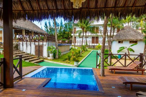 a resort with a swimming pool and a house at Pousada Coco Cabana in Camocim