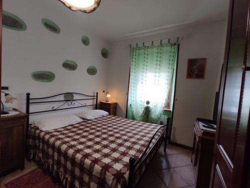 1 dormitorio con 1 cama con cortina verde y ventana en Agriturismo Alpi, en Roccaforte Ligure