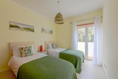 two beds in a room with a window at Penthouse Cassia in Cabanas de Tavira