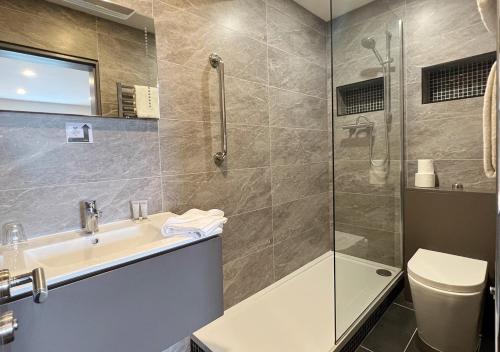 uma casa de banho com um chuveiro, um lavatório e um WC. em Bella Vista Hotel & Self Catering Suites em Cobh
