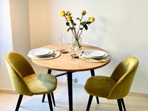 stół z krzesłami i waza z żółtymi kwiatami w obiekcie Marceau Central Flat w Nicei