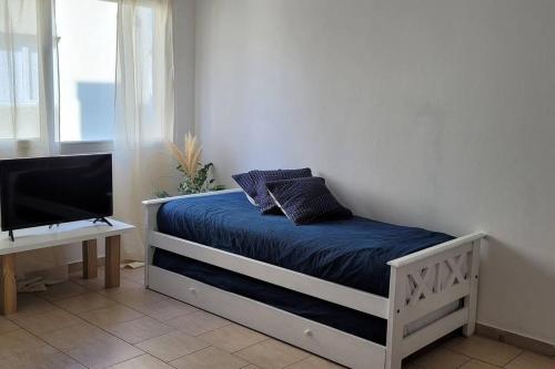 1 dormitorio con 1 cama con sábanas azules y TV en Alamos Tandil en Tandil