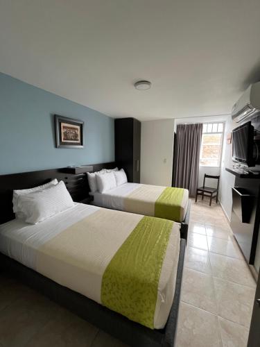 a hotel room with two beds and a television at Hotel Tupinamba Neiva in Neiva