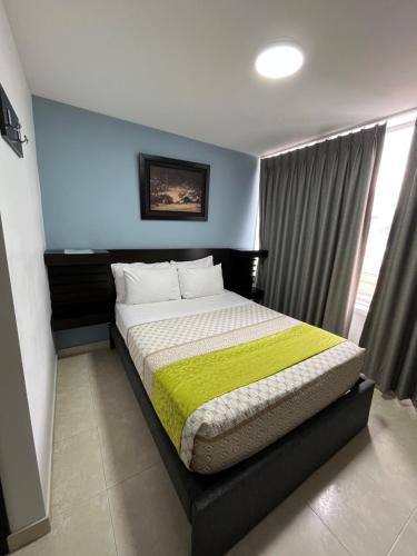 a bedroom with a bed with a green blanket on it at Hotel Tupinamba Neiva in Neiva