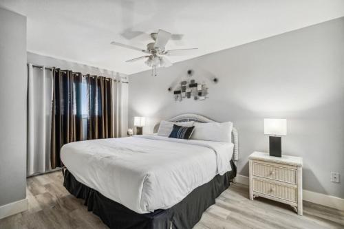 a white bedroom with a bed and a ceiling fan at The Summit 531 in Panama City Beach