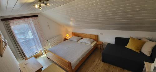 1 dormitorio pequeño con 1 cama y 1 sofá en Apartments & Hostel Bohinj, en Bohinj