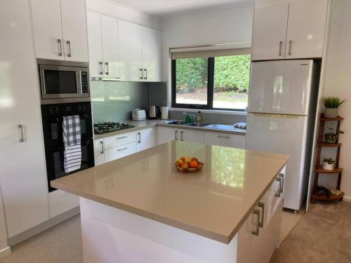 uma cozinha branca com uma taça de fruta no balcão em Little Haven in Mount Eliza with views em Mount Eliza
