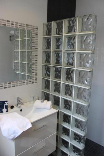 a bathroom with a sink and a wall of glass shelves at Hotel Bahia in Cala Santandria