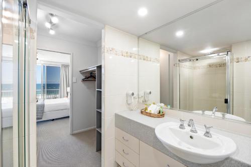 a white bathroom with a sink and a mirror at Elouera Beachside Bliss 2 Bedroom Apartment in Maroochydore