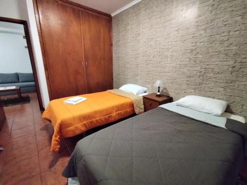 Habitación con 2 camas y pared de ladrillo en Apartamentos Lisboa en Vila do Porto
