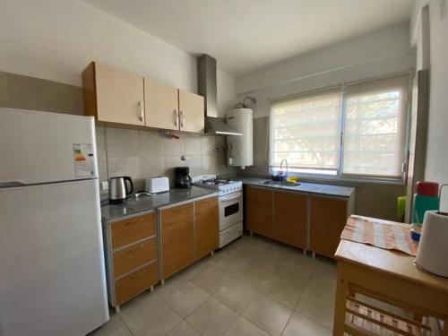 a kitchen with a white refrigerator and wooden cabinets at Muy lindo departamento! in Puerto Madryn