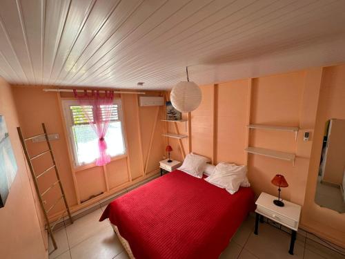 a bedroom with a red bed and a window at Les Gites Josiane in Les Trois-Îlets