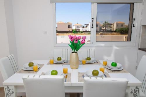 a dining room table with a vase of flowers on it at Villa suncity Boutique Beachfront in Ayia Napa