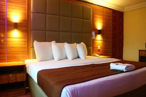 um quarto de hotel com uma cama grande com almofadas brancas em Presken K-ONE em Ikeja