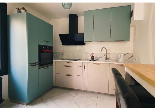 a kitchen with green and white cabinets and a counter at Maison chaleureuse in Villeneuve-sur-Lot