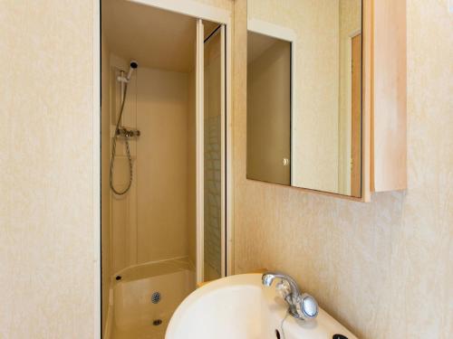 La salle de bains est pourvue d'un lavabo, d'une douche et d'un miroir. dans l'établissement Mobile Home in La Londe-les-Maures with Terrace, à La Londe-les-Maures