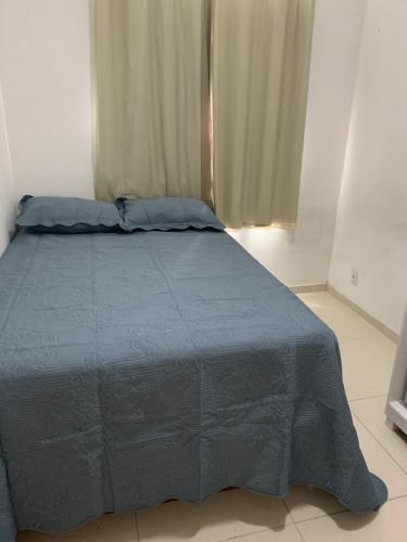 a bed with a blue comforter in a bedroom at Apartamento completo Ilheus in Ilhéus