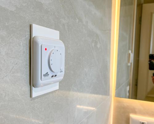 a white soap dispenser on a wall next to a mirror at Pousadinha Campos in Campos do Jordão