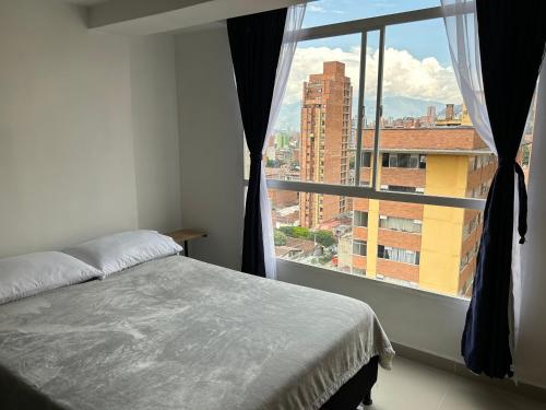a bedroom with a bed and a large window at Hermoso loft en medellin in Medellín