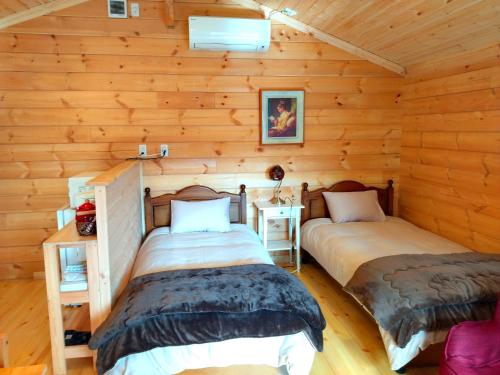 2 łóżka w pokoju z drewnianymi ścianami w obiekcie 藤のヴィラ チェリー棟 Self Check-in w mieście Aso