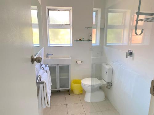 a white bathroom with a toilet and a sink at Glenelg Holiday Apartments-The Broadway in Glenelg