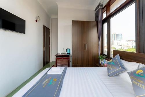 ドンホイにあるTan Hoang Minh Hotelの大きな窓のあるベッドのある寝室