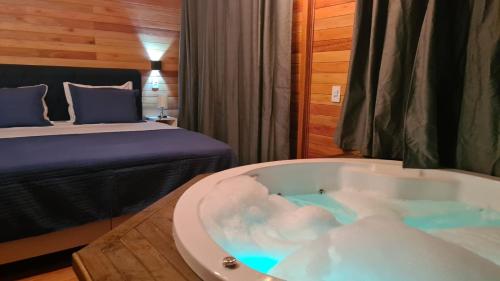 um quarto com uma banheira e uma cama em Chalé Vista Das Araucárias em Urubici
