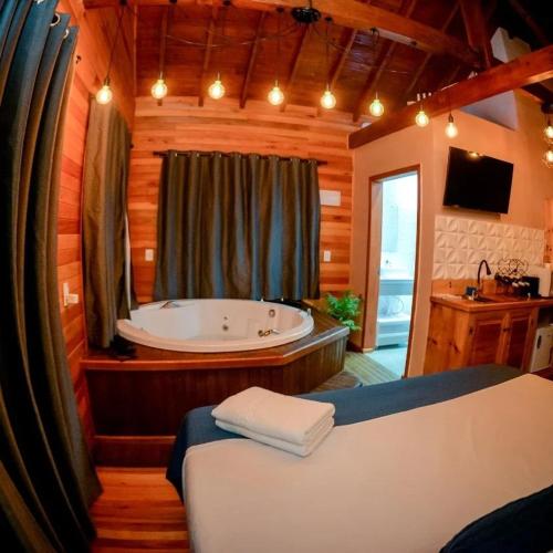 a bathroom with a tub and a bed in a room at Chalé Vista Das Araucárias in Urubici