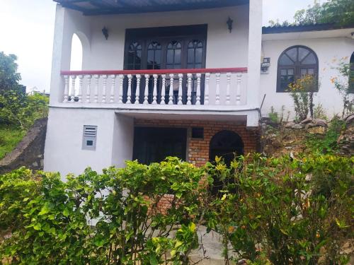 une maison blanche avec un balcon sur une colline dans l'établissement Zuni`s Home Stay, à Kandy