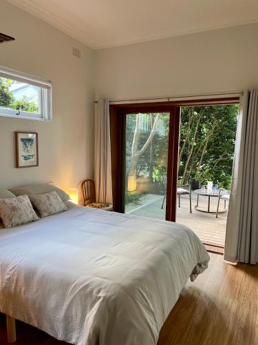 a bedroom with a bed and a sliding glass door at Tranquil Garden Apartment with living room in Wollongong