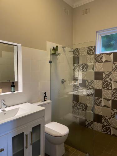 een badkamer met een douche, een toilet en een wastafel bij Tranquil Garden Apartment with living room in Wollongong