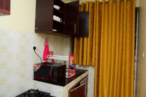 a microwave on a counter in a kitchen with yellow curtains at Elegant studio apartment in Kitengela 
