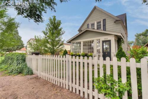 a white picket fence in front of a house at The Historic Blue Bird Cottage in Colorado Springs